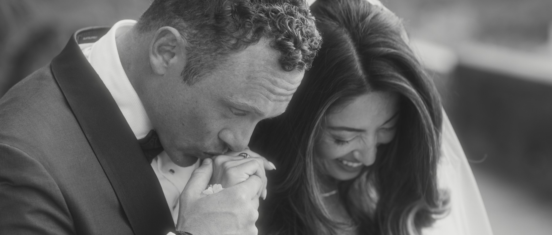 Patrick kissing Morgan’s hand in black and white